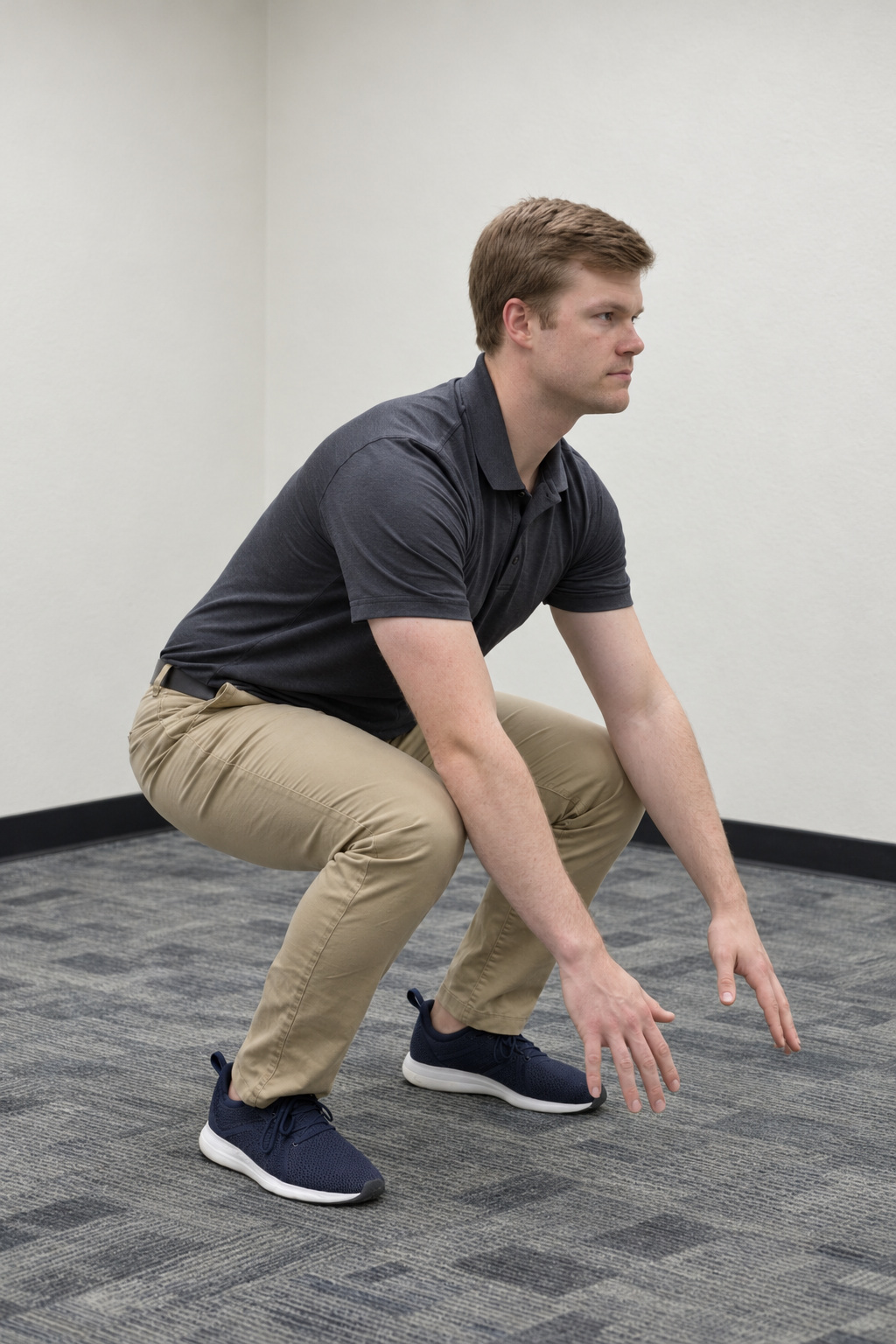 Man in plainclothes squatting in a doctor's office for motion analysis.